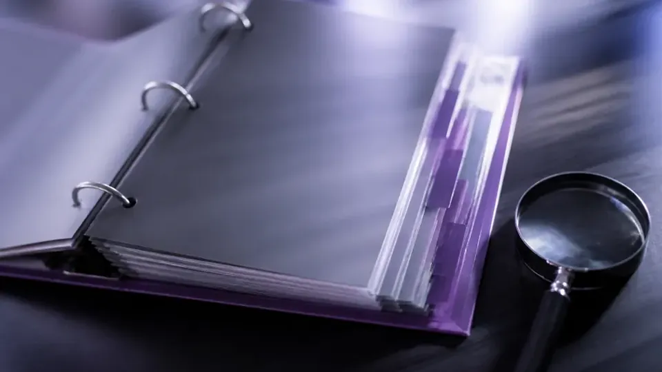 A ring binder open at a page with a bar chart, a magnifying glass beside it.