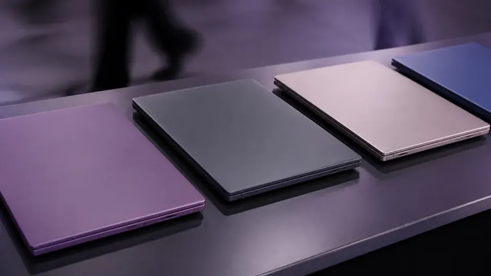 Laptops and closed folders lined up on a dark desk in a newsroom office.