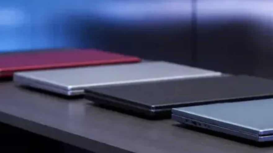 Closed laptops and folders in a row on a long desk, lit from one side.