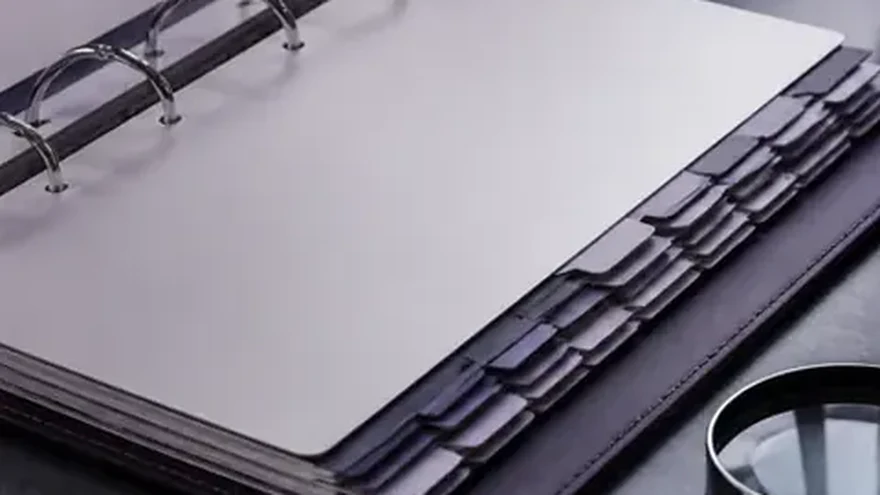 An open ring binder with a blank sheet resting on a keyboard.